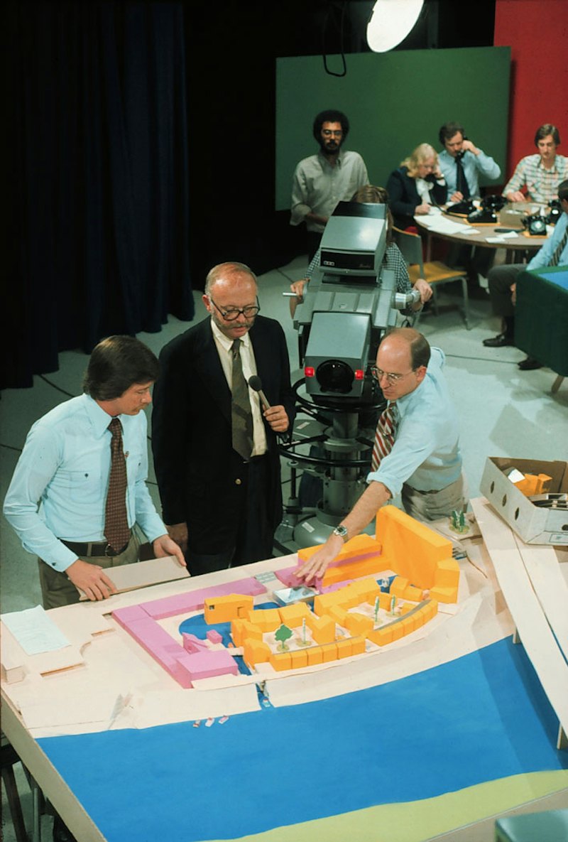 Centerbrook Principal Chad Floyd, right, gestures over a model of downtown Dayton, Ohio during a televised Design-A-Thon. The narrator, center, is Charles W. Moore, who co-founded Centerbrook’s forerunner firm, Moore Grover Harper.